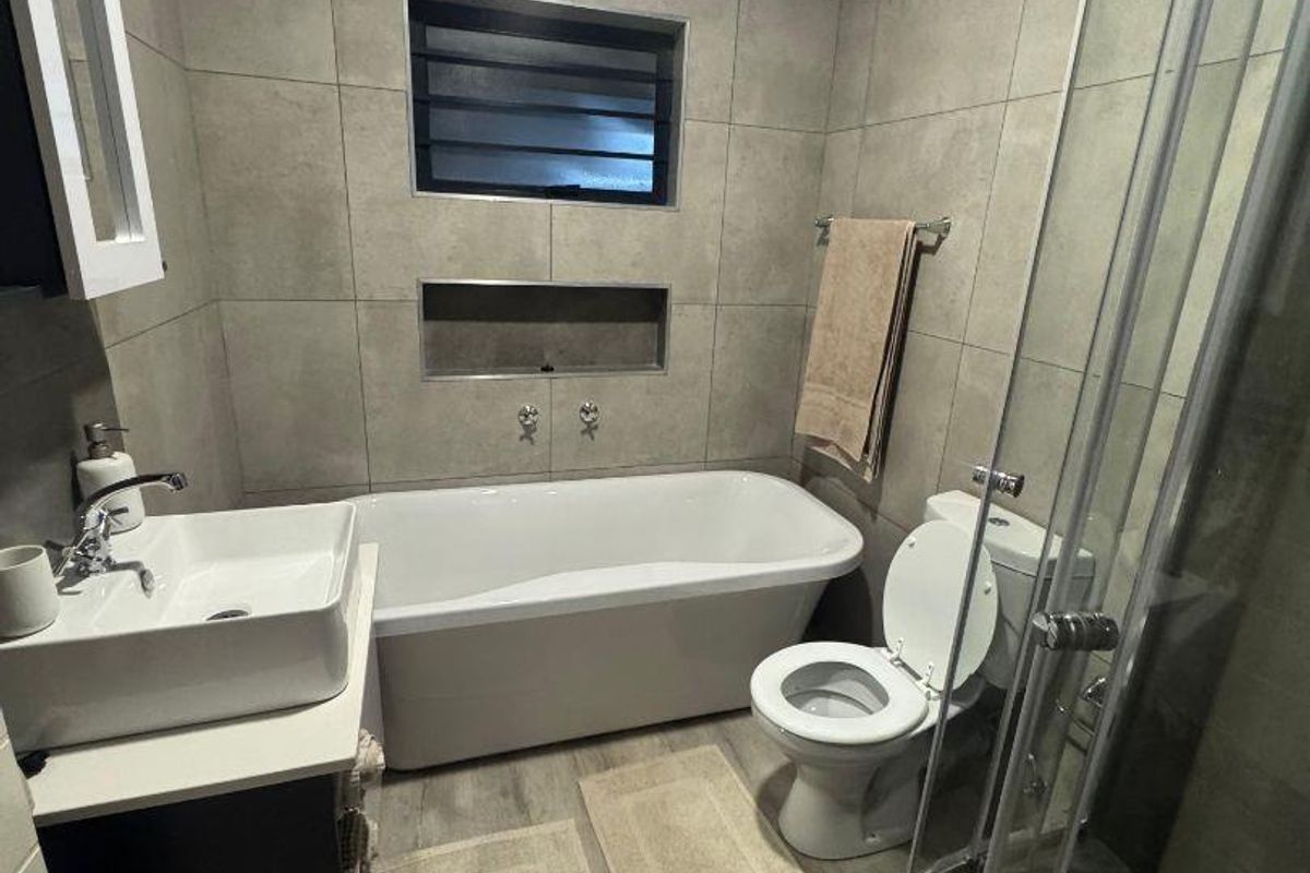 Modern bathroom featuring a freestanding bathtub, separate shower enclosure, vanity basin, and neutral wall tiling with a convenient recessed niche.