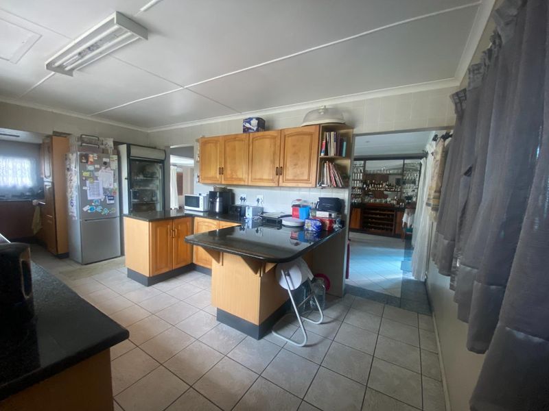 A functional kitchen featuring wooden cabinetry, granite countertops, and tiled flooring, offering a traditional layout with potential for modern updates.