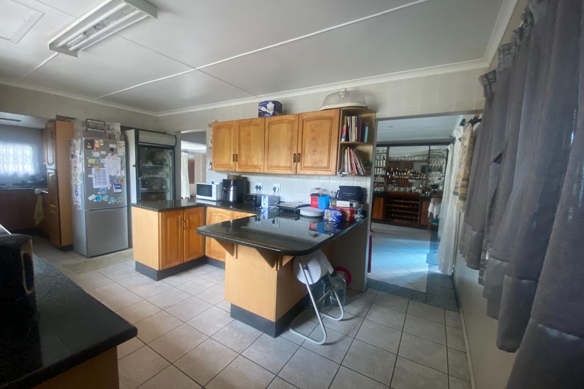 A functional kitchen featuring wooden cabinetry, granite countertops, and tiled flooring, offering a traditional layout with potential for modern updates.