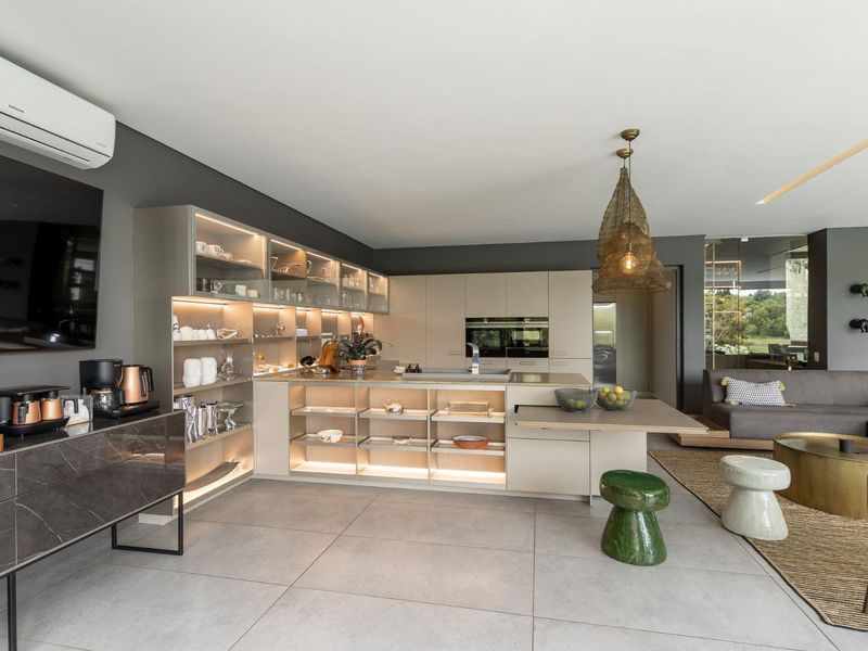 Modern open-plan living area featuring a sleek kitchen with integrated appliances, custom cabinetry, and large format floor tiles, seamlessly flowing into the lounge space.