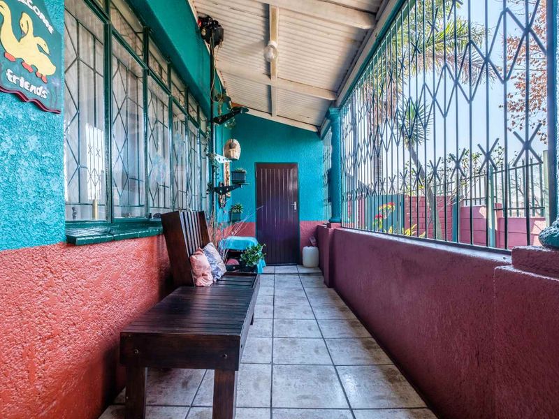 A covered patio area featuring tiled flooring, security bars, and an exposed beam ceiling, providing a functional outdoor transition space.