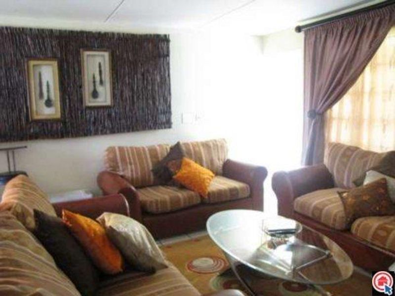 A living room area featuring neutral walls, window treatments, and natural light, providing a functional space for relaxation.