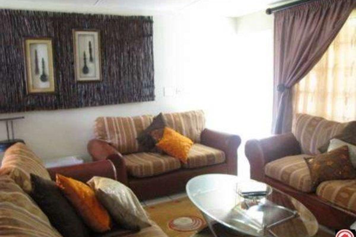 A living room area featuring neutral walls, window treatments, and natural light, providing a functional space for relaxation.