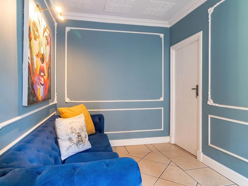 A well-maintained living area featuring decorative wall molding, ornate ceiling detailing, and tiled flooring.