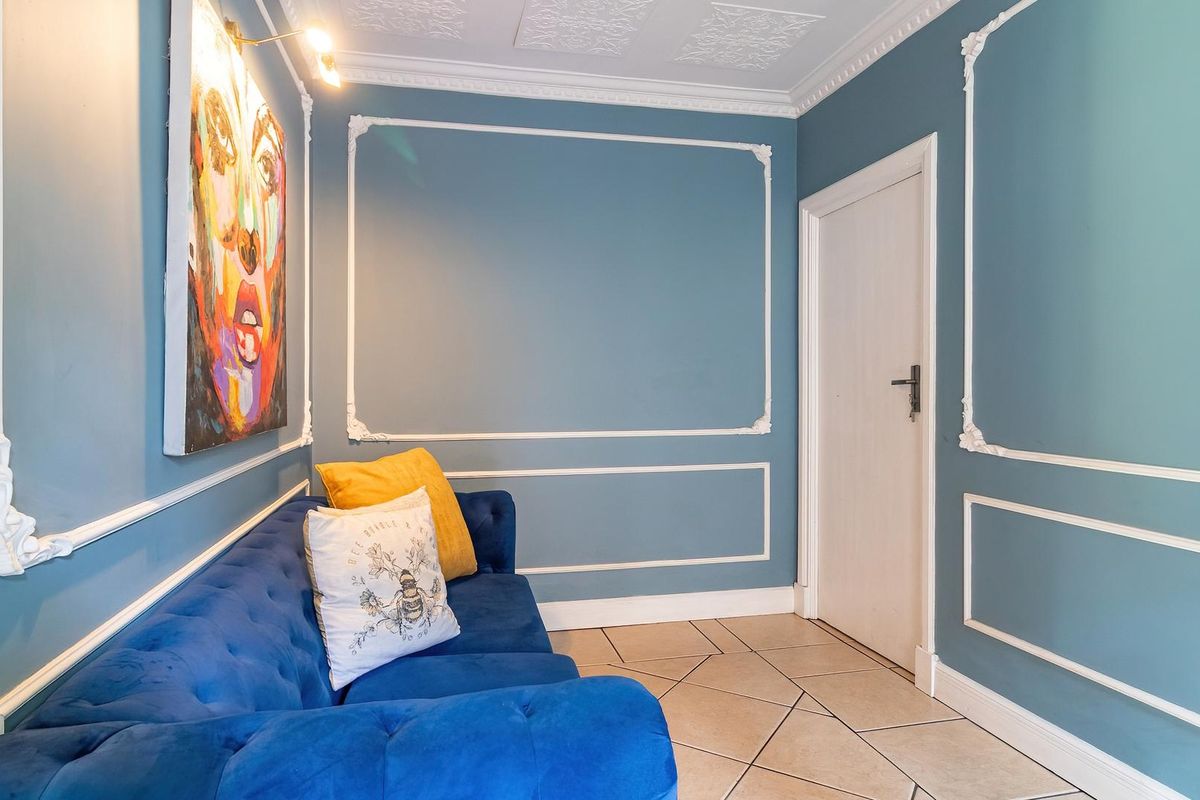 A well-maintained living area featuring decorative wall molding, ornate ceiling detailing, and tiled flooring.