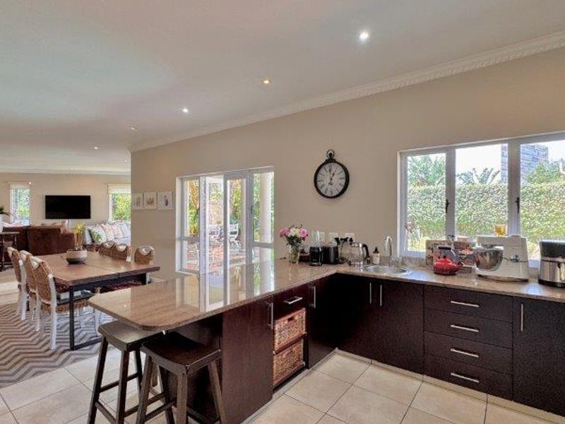 Spacious open-plan kitchen and dining area featuring dark wood cabinetry, granite countertops, and seamless access to the outdoor patio through sliding glass doors.