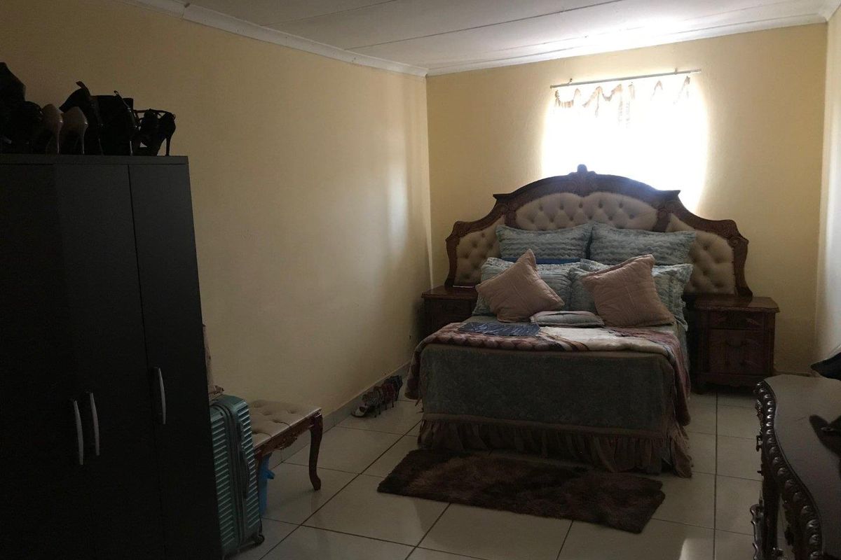 A bedroom featuring tiled flooring and a neutral wall finish, providing a functional space for rest.