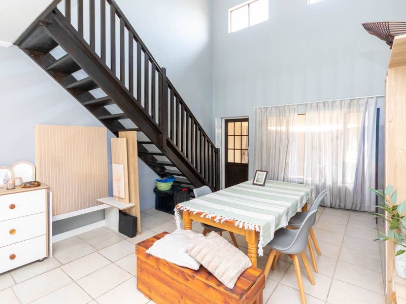 Open plan living area featuring high ceilings, clerestory windows, and a prominent timber staircase leading to the upper level.