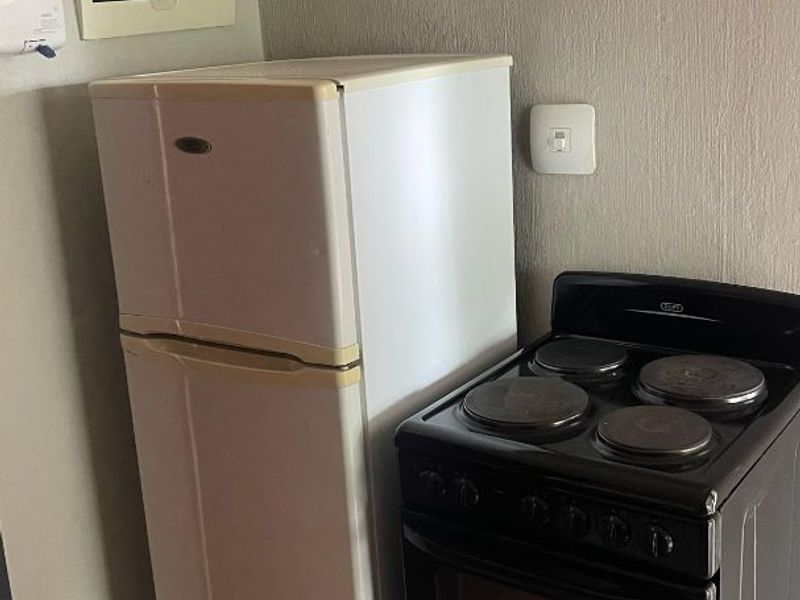 A functional kitchen corner featuring tiled flooring, an electrical distribution board, and a security alarm keypad.