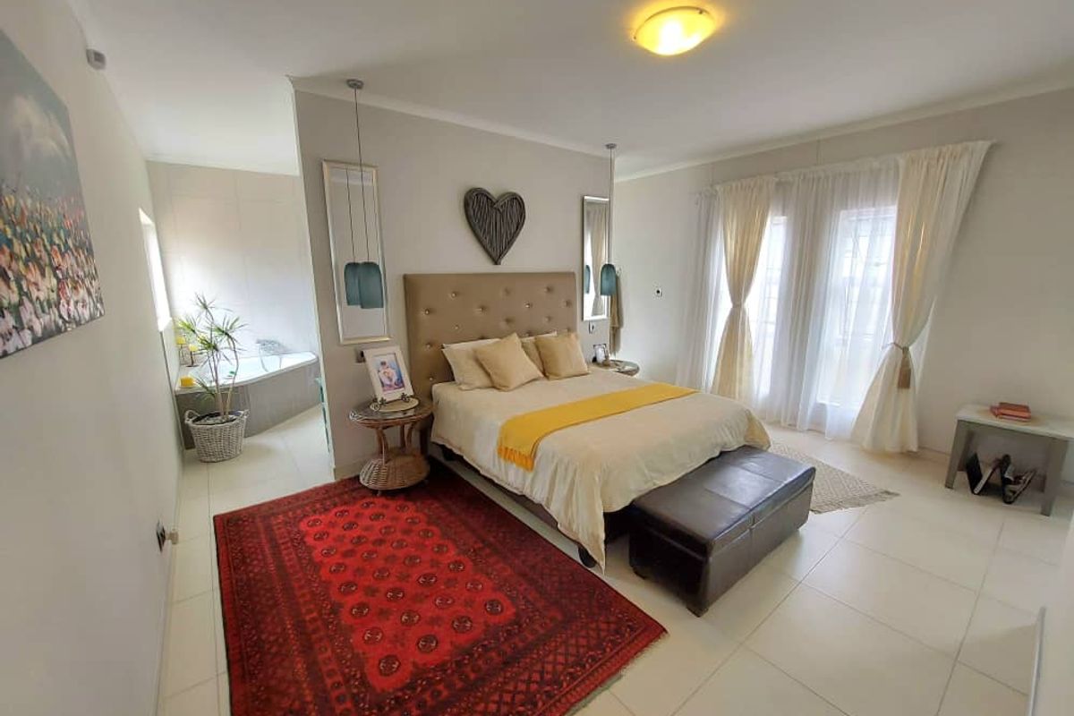 Spacious bedroom featuring tiled flooring, neutral walls, and an open-plan en-suite bathroom area with a built-in corner bathtub.