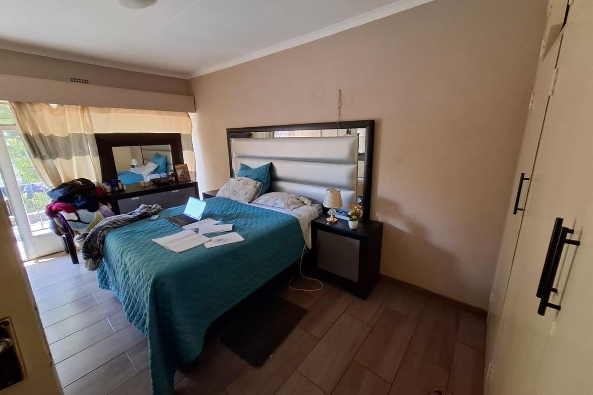 A bedroom featuring tiled flooring, built-in cupboards, and a sliding door providing access to an outdoor area.