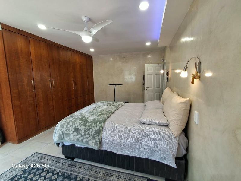 Spacious bedroom featuring extensive built-in wooden cabinetry, modern recessed lighting, a ceiling fan, and neutral wall finishes.