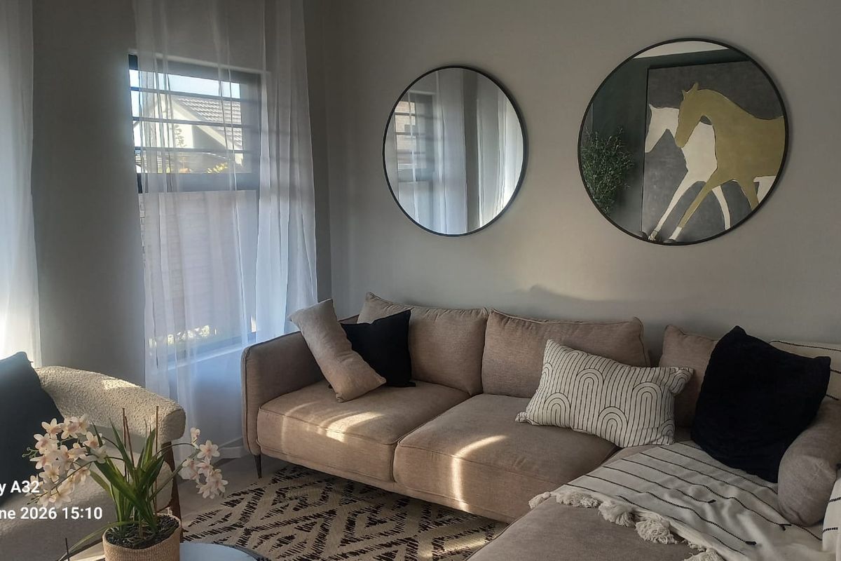 A cozy living room area featuring neutral wall tones and natural light through a side window.