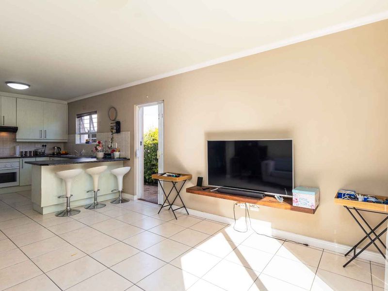 Open-plan living area featuring a functional kitchen with built-in cabinetry, oven, hob, and tiled flooring, seamlessly connected to the living space.