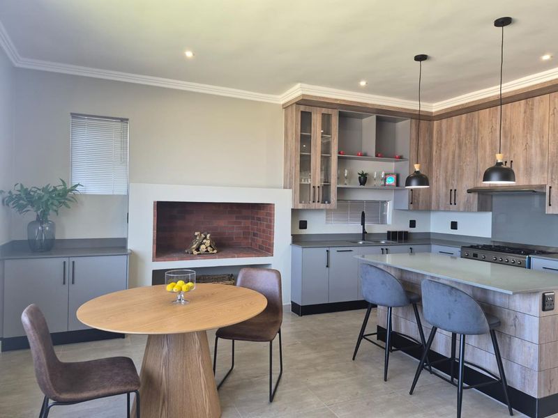 Modern open-plan kitchen featuring a built-in fireplace, central island with breakfast bar, contemporary cabinetry, and high-quality finishes throughout.