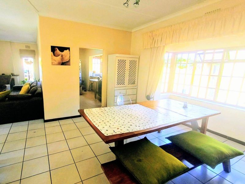 Open plan dining area featuring tiled flooring and a large bay window, providing a bright and functional space connected to the living area.