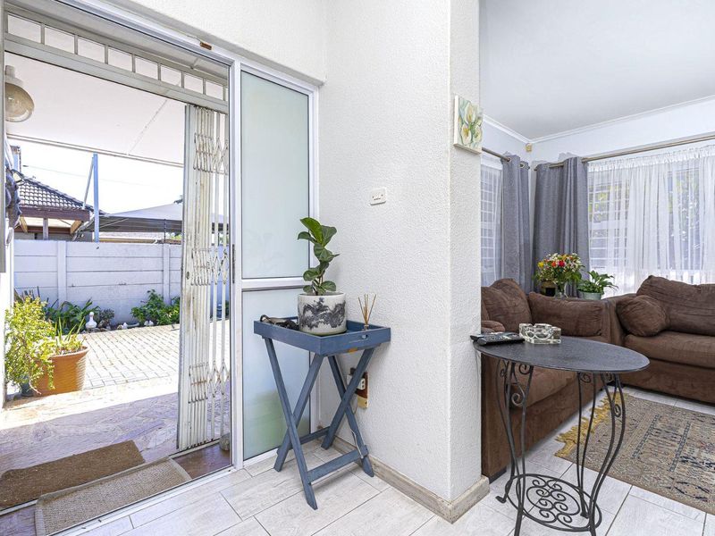 A living room area featuring tiled flooring and a sliding glass door with a security gate leading to an outdoor patio space.