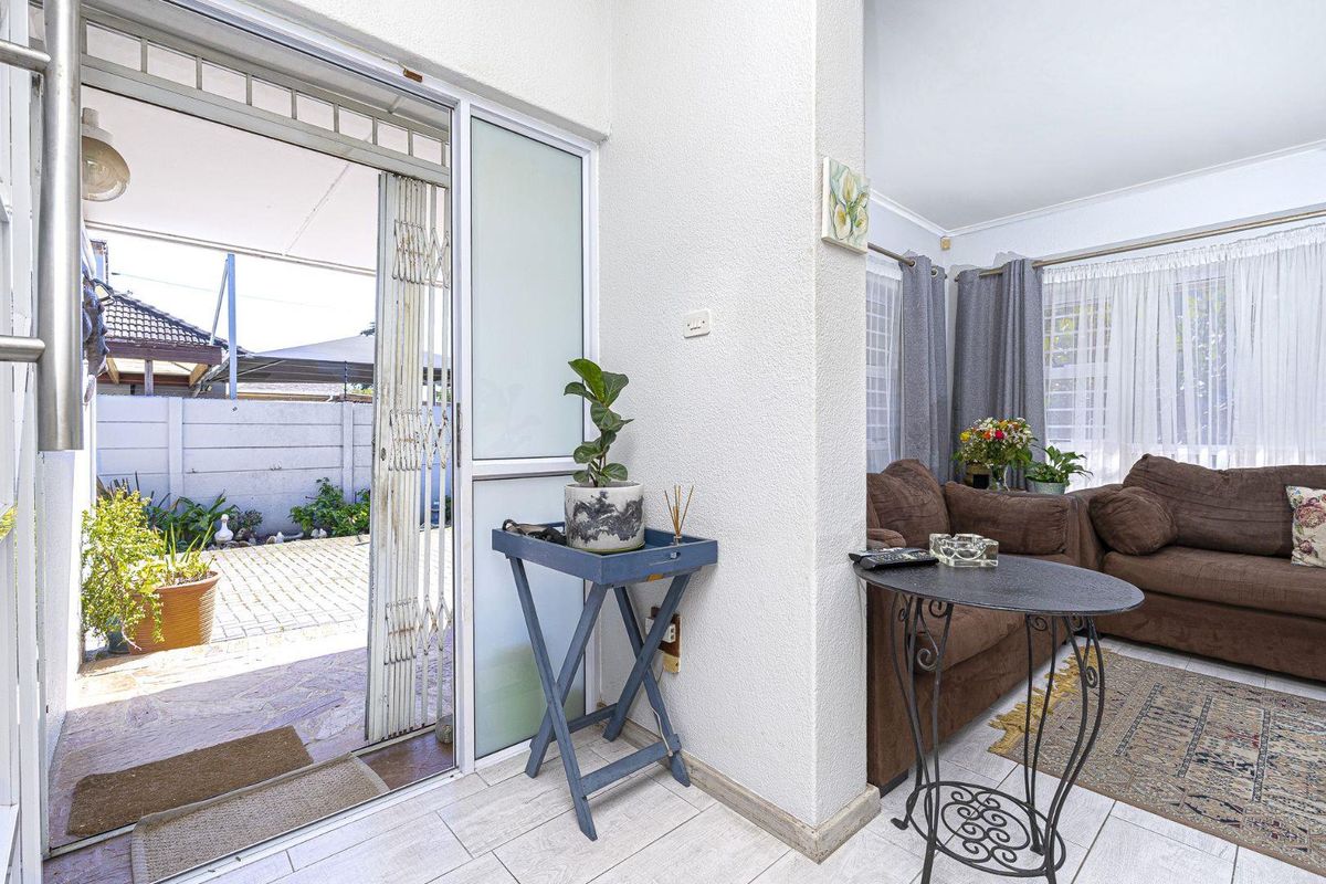 A living room area featuring tiled flooring and a sliding glass door with a security gate leading to an outdoor patio space.