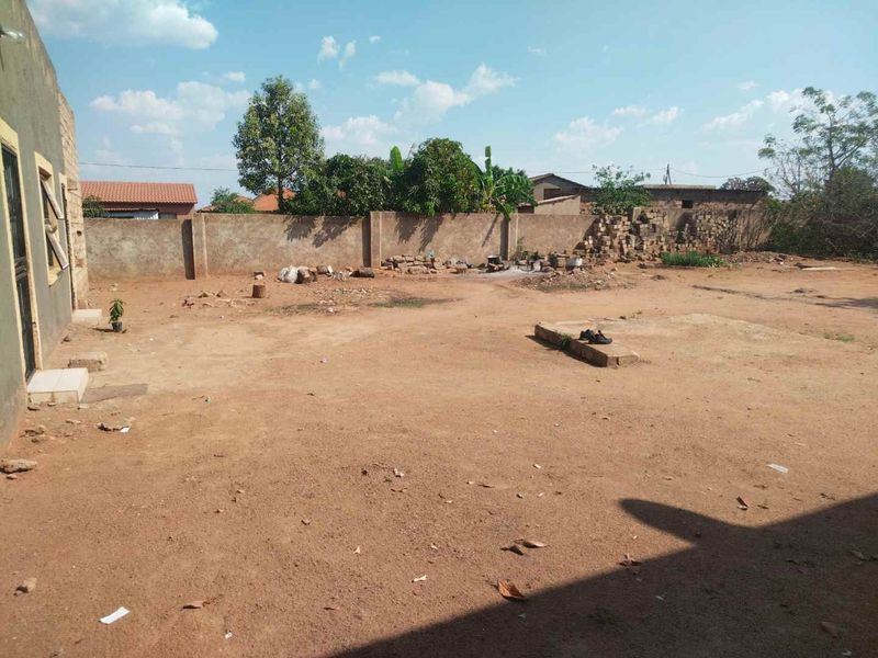 A spacious, unlandscaped rear yard area enclosed by a perimeter boundary wall, offering significant potential for garden development and outdoor improvement.