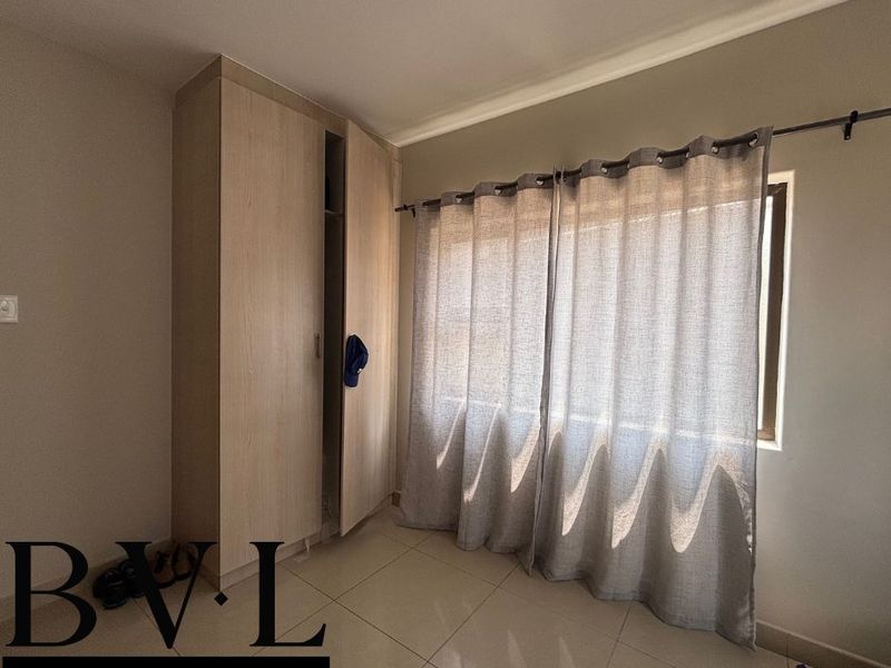 A bright, neutral bedroom featuring tiled flooring and a built-in wardrobe, offering a clean and functional space ready for personalization.