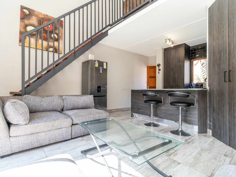 Open plan living area featuring a modern kitchen with island, tiled flooring, and a staircase leading to the upper level.