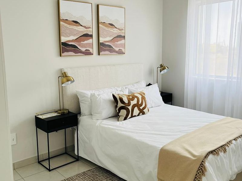 A well-maintained bedroom featuring neutral wall tones, tiled flooring, and a classic tongue and groove ceiling with natural light.