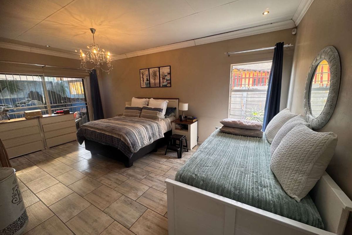 Spacious bedroom featuring tiled flooring, crown molding, recessed lighting, and a sliding glass door with security bars providing access to the exterior.
