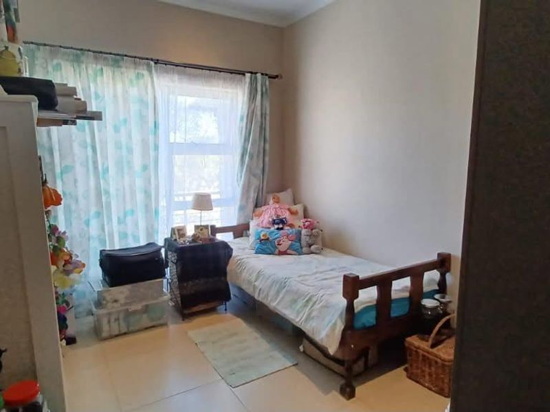 A bedroom featuring tiled flooring and a sliding glass door providing natural light.