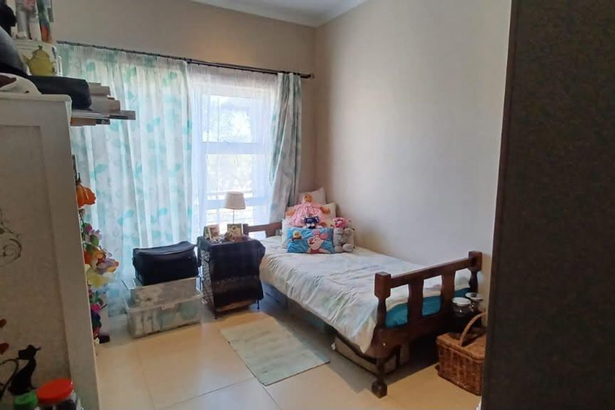 A bedroom featuring tiled flooring and a sliding glass door providing natural light.