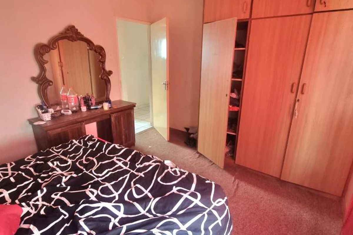 A bedroom featuring built-in wooden cabinetry and carpeted flooring, providing functional storage space.