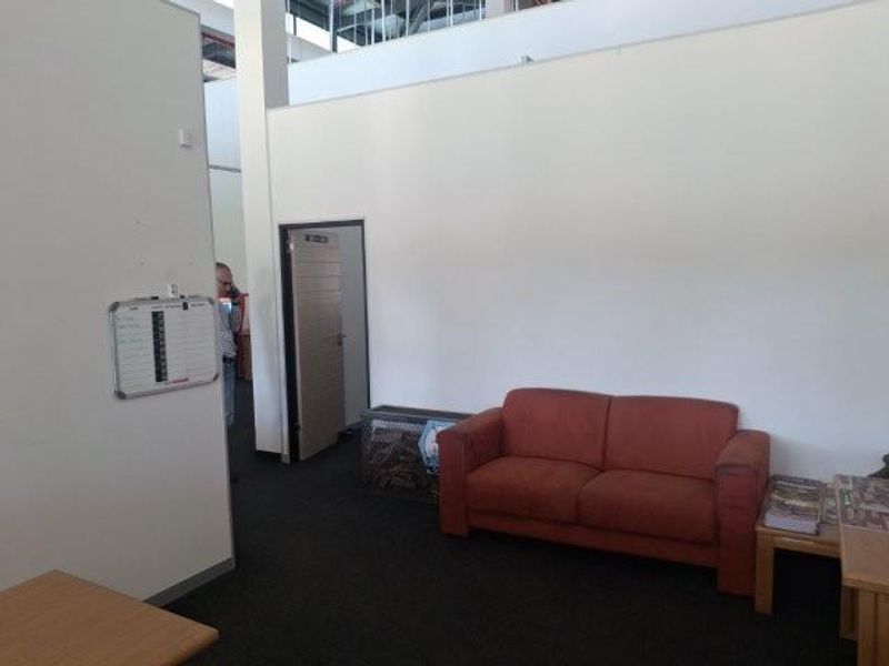 A functional office space featuring carpeted flooring, high ceilings, and a neutral wall finish, suitable for a professional work environment.