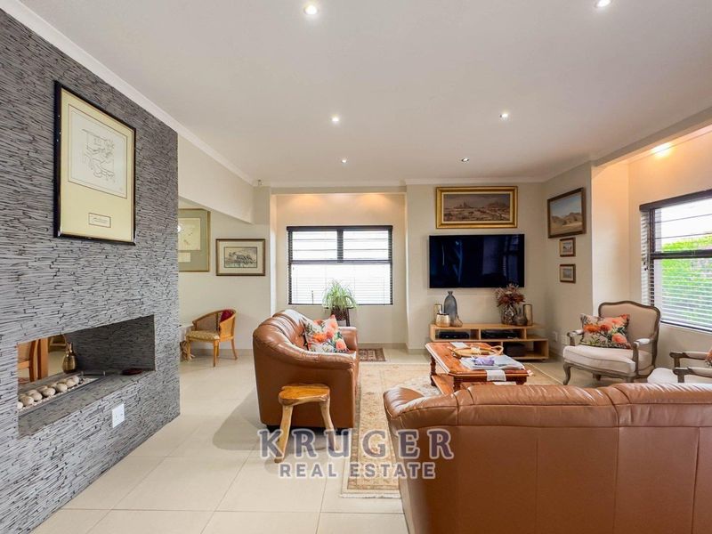 Spacious living room featuring a modern stone-clad feature wall with a built-in fireplace, tiled flooring, and recessed downlighting.