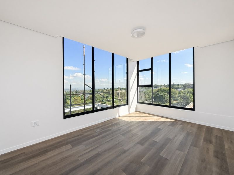 A bright, empty living area featuring expansive floor-to-ceiling windows with panoramic views and modern laminate wood flooring.