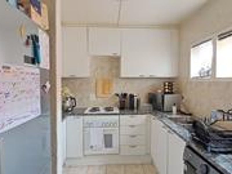 A functional kitchen featuring white cabinetry, granite countertops, a built-in oven, and an electric hob, providing a practical workspace for daily cooking.
