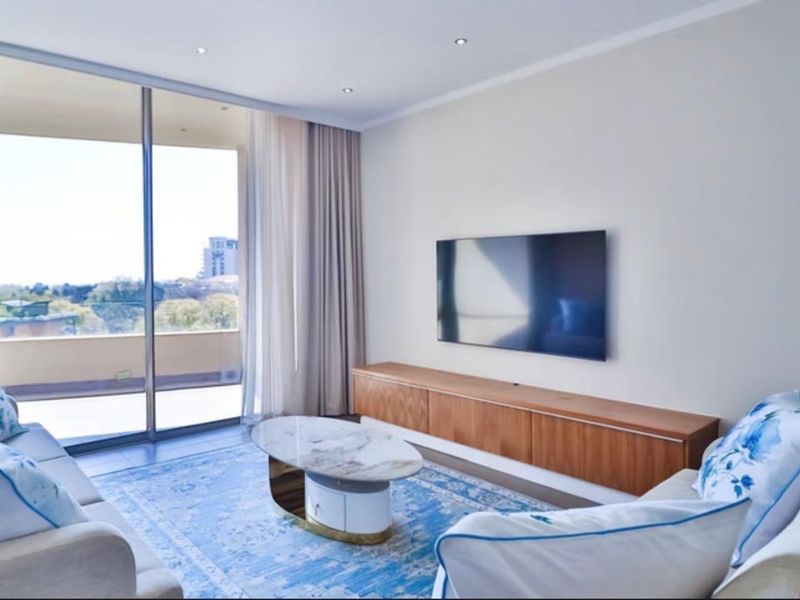 Modern living room featuring recessed lighting, built-in cabinetry, and large sliding glass doors opening to a balcony with scenic views.