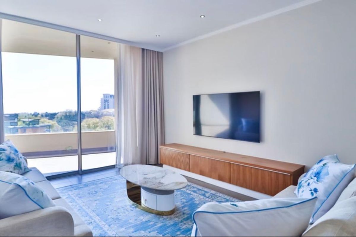Modern living room featuring recessed lighting, built-in cabinetry, and large sliding glass doors opening to a balcony with scenic views.