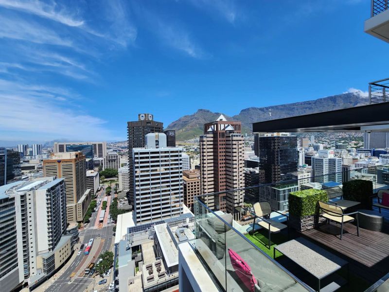 Elevated balcony view overlooking the city skyline and Table Mountain, featuring modern glass balustrades and timber decking.