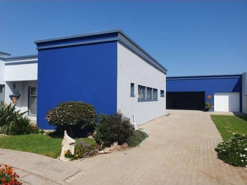 Front elevation of a modern house featuring a paved driveway, attached garage, and distinctive blue and white exterior paintwork.