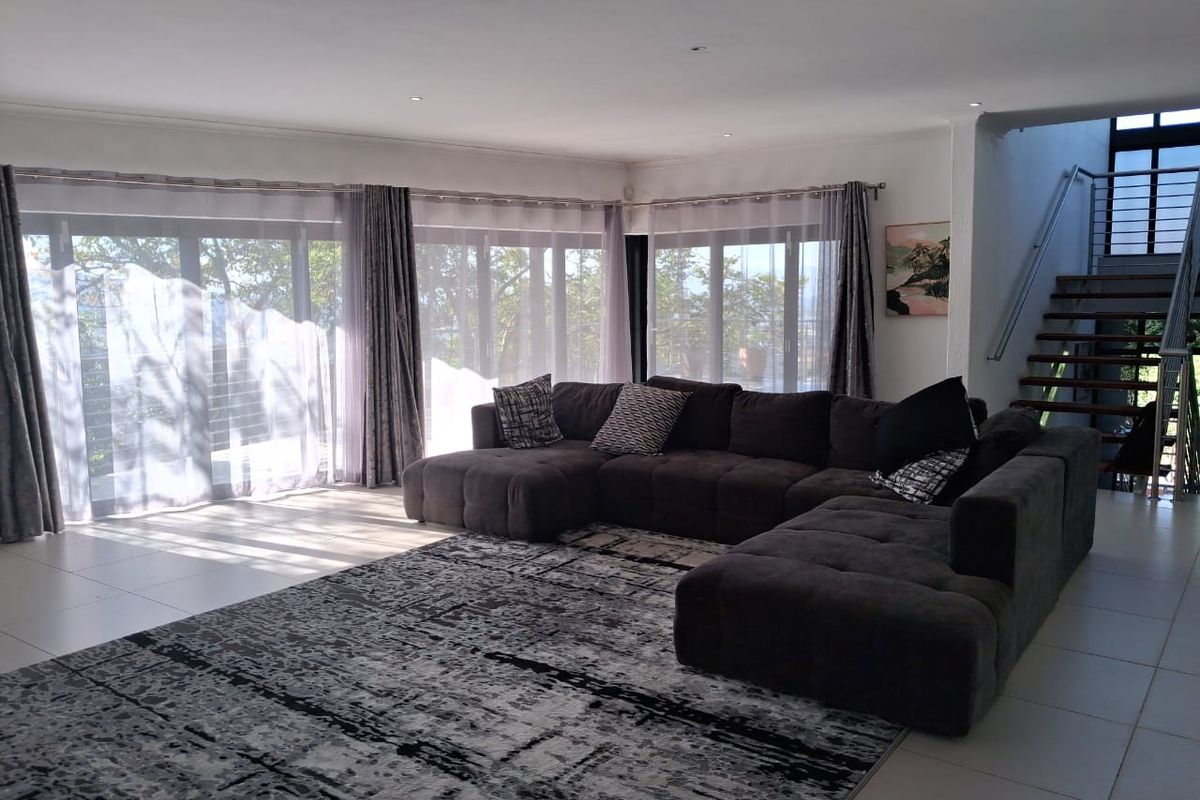 Spacious living room featuring large sliding glass doors, tiled flooring, recessed lighting, and an open staircase with a modern metal railing.