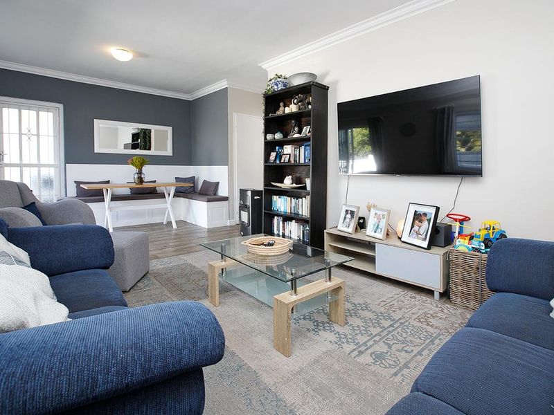 Open plan living and dining area featuring laminate flooring, crown molding, and a built-in dining bench with a modern, neutral color palette.