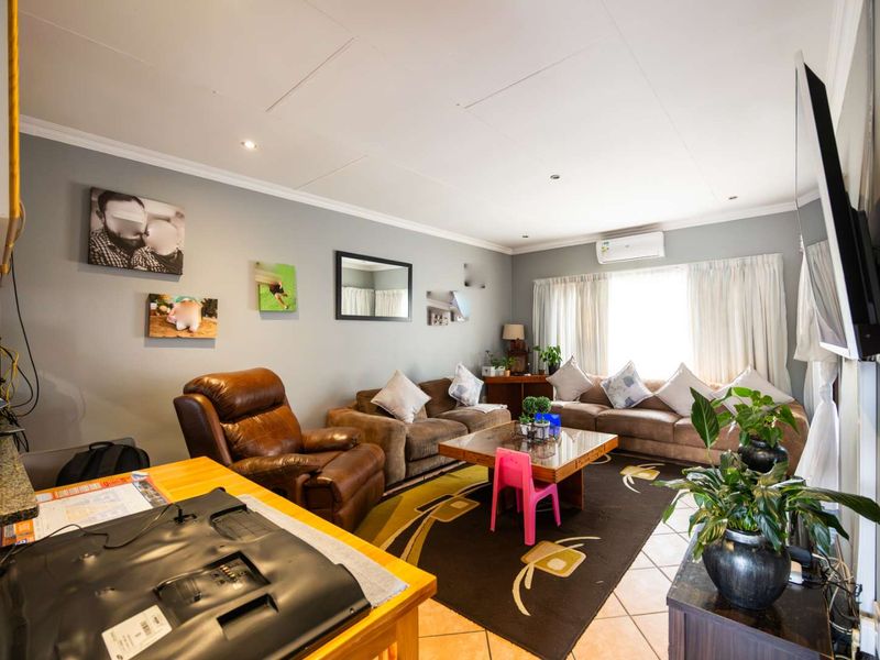 Open-plan living area featuring tiled flooring, recessed downlighting, and a wall-mounted air conditioning unit, providing a functional and connected space.
