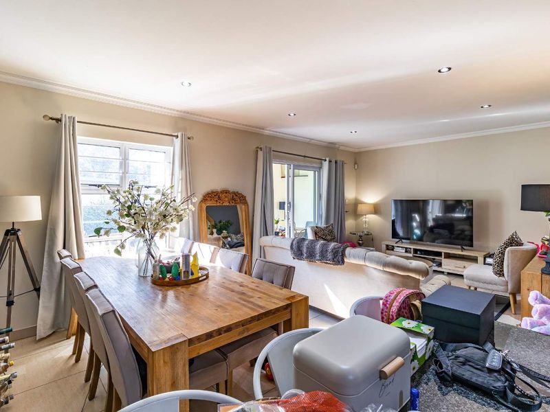 Spacious open-plan living and dining area featuring tiled flooring, recessed downlighting, and sliding glass doors leading to an outdoor space.