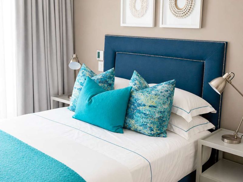 A well-maintained bedroom featuring neutral wall tones, floor-to-ceiling curtains, and integrated electrical fixtures.