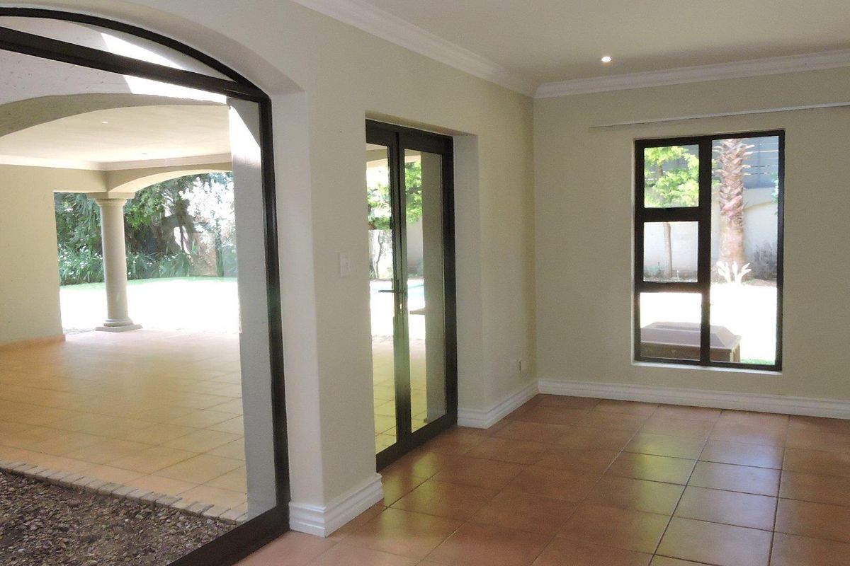 A bright, empty living area featuring tiled floors, recessed lighting, and direct access to a covered patio through double glass doors.