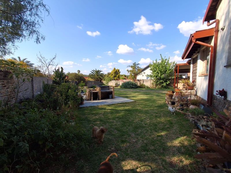 Spacious rear garden featuring a lawn, brick boundary walls, and a built-in braai area, providing a functional outdoor space for relaxation and entertainment.