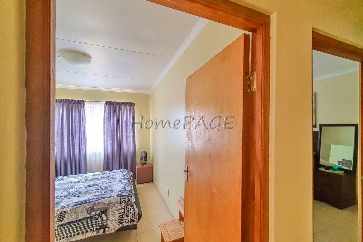 A view into a bedroom featuring tiled flooring, wooden door frames, and a ceiling-mounted light fixture.
