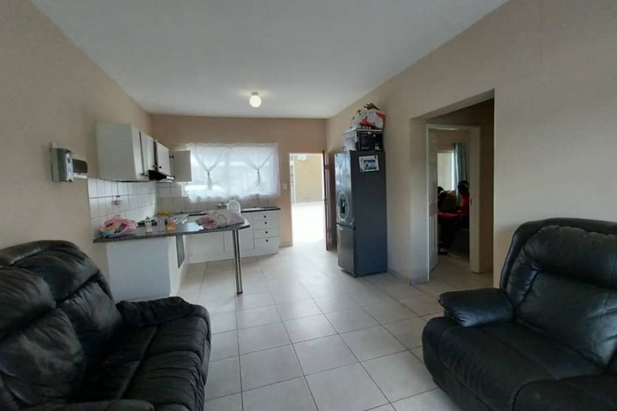 Open plan living area featuring tiled flooring and a functional kitchen with built-in cabinetry, providing a practical layout for daily living.