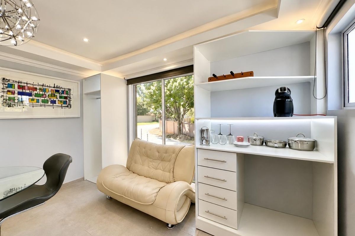 A bright living area featuring modern built-in cabinetry, recessed ceiling lighting, and large sliding glass doors that provide ample natural light.