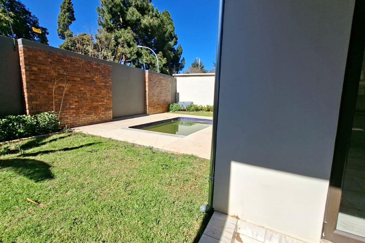A private rear garden featuring a small swimming pool, paved surround, and high perimeter brick walls for added privacy.