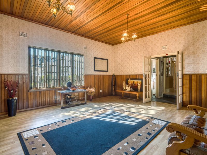 Spacious living room featuring timber ceiling and wall paneling, laminate flooring, and classic french doors leading to the hallway.